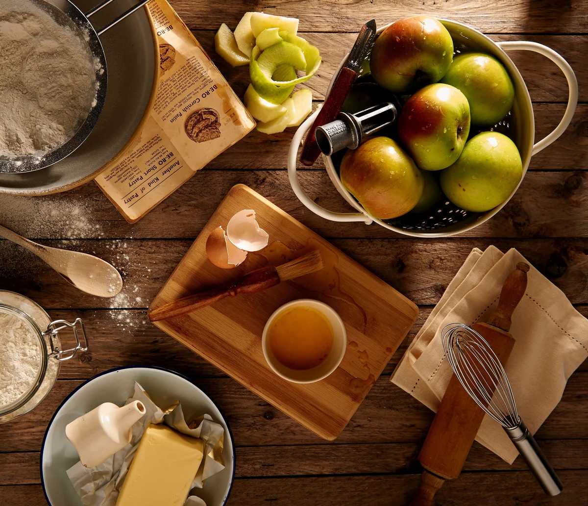 Apples, flour and baking ingredients on a wooden kitchen table